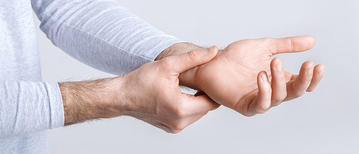 man pressing on his wrist as if he is in pain