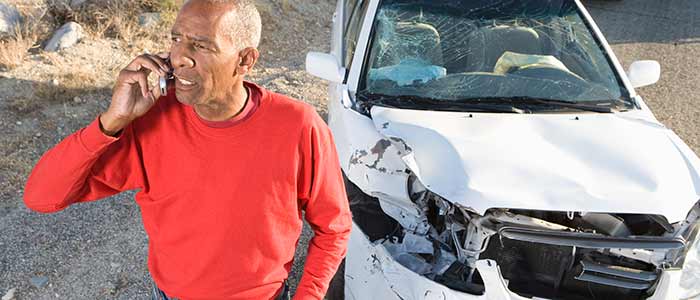 man on phone with wrecked car in the background