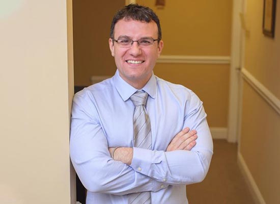 Dr. Alec Khlebopros in front of his office interior - Chiropractic Charlotte