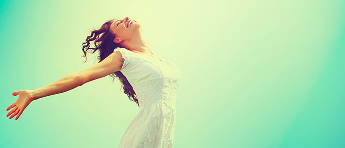 lady in dress with her arms out and smiling. the photo has a green background